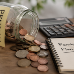 A tipped-over jar labelled Pension spilling coins across a desk beside a calculator and a notebook headed Pension Plan